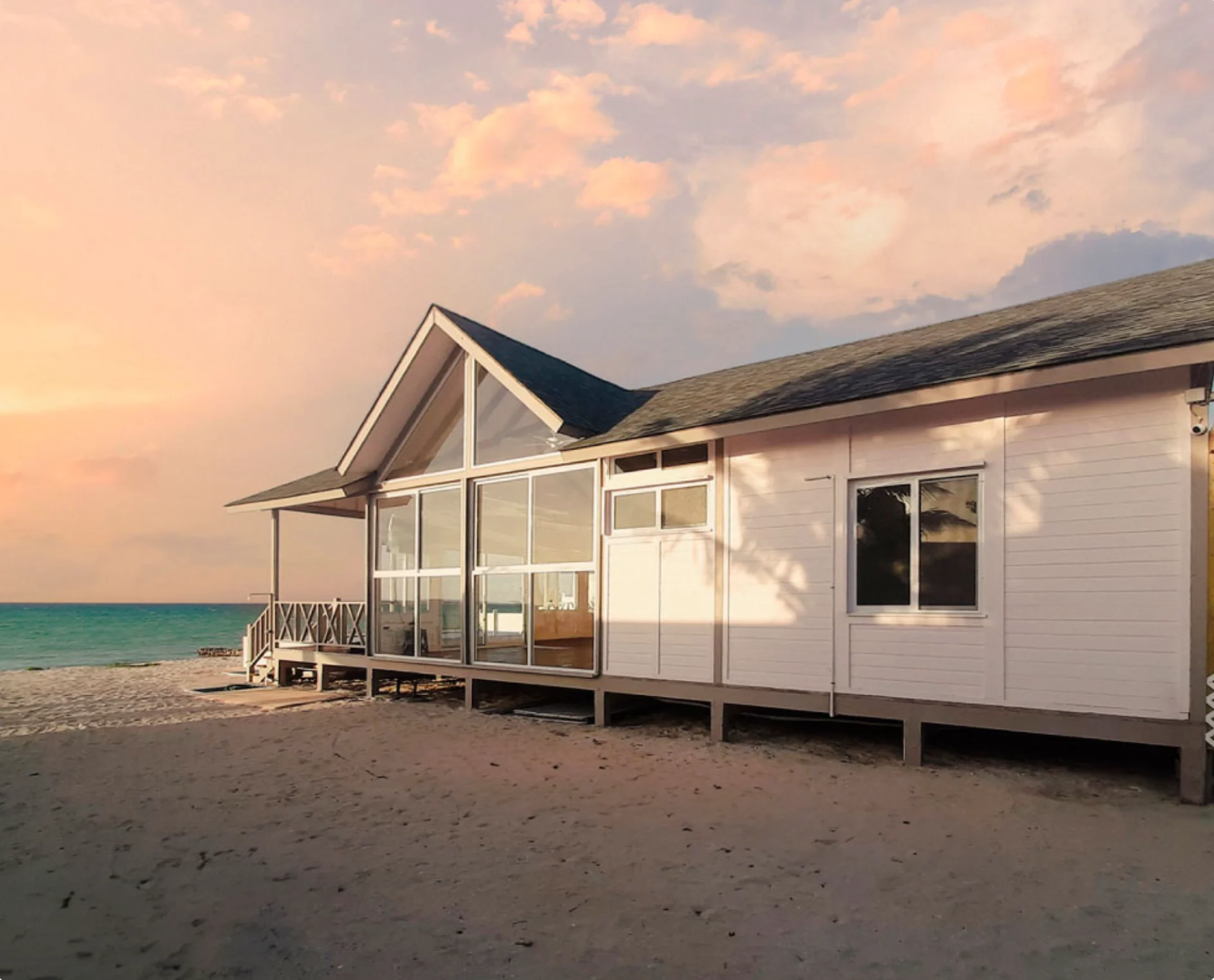 White coastal cabin by the sea at sunset